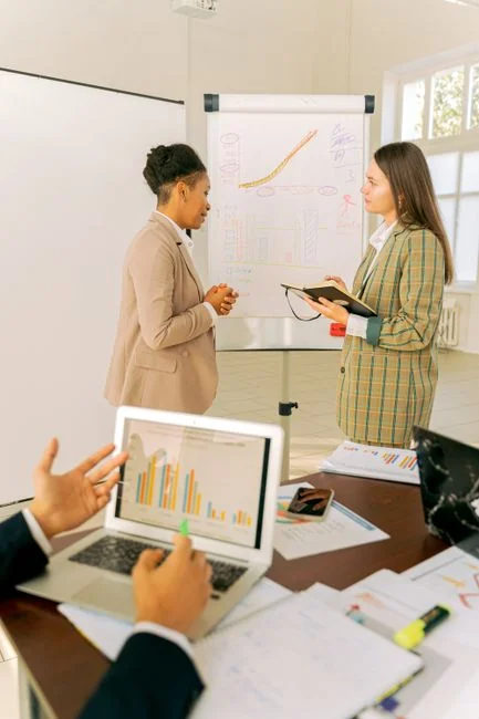Un espace de travail moderne où des mains analysent des données marketing sur un ordinateur portable et des documents papier.